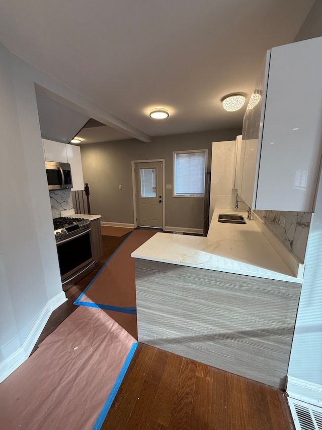 kitchen featuring white cabinets, dark wood finished floors, stainless steel appliances, light countertops, and a sink