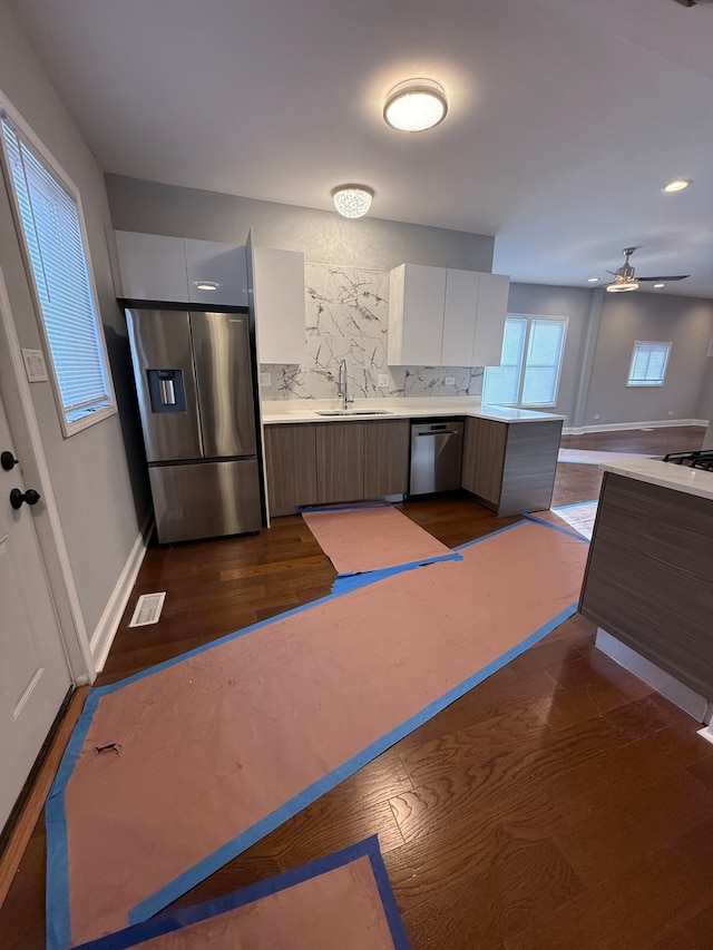 kitchen with stainless steel appliances, light countertops, brown cabinetry, a sink, and modern cabinets