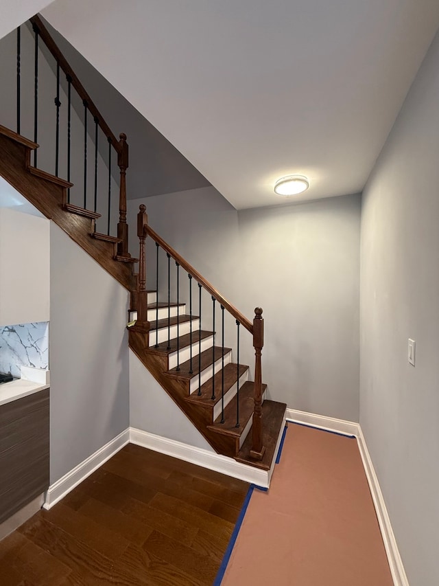 stairway with wood finished floors and baseboards