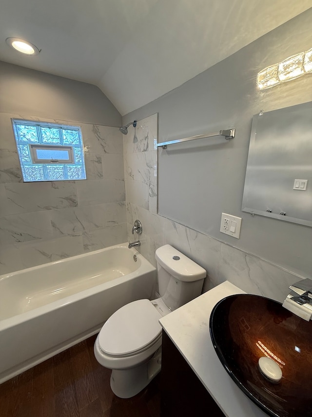 bathroom featuring wood finished floors, vaulted ceiling, vanity, shower / washtub combination, and tile walls