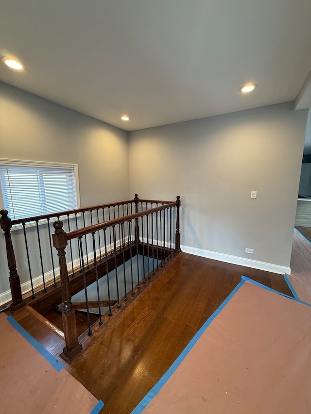 stairway with baseboards, wood finished floors, and recessed lighting