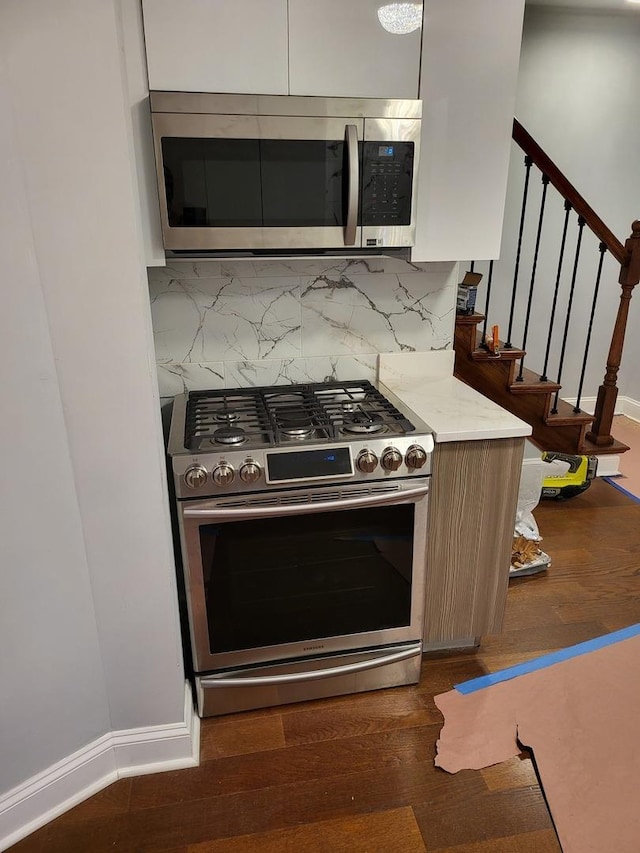 kitchen with light countertops, appliances with stainless steel finishes, dark wood-type flooring, and tasteful backsplash