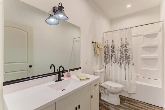 full bathroom featuring hardwood / wood-style floors, vanity, toilet, and shower / tub combo