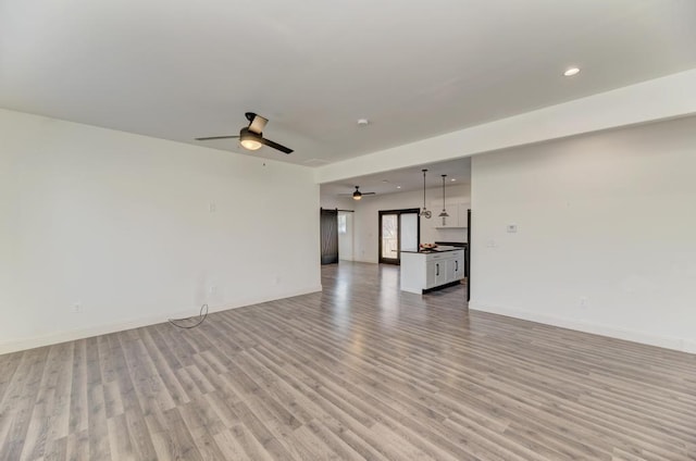 unfurnished living room featuring ceiling fan and light hardwood / wood-style flooring