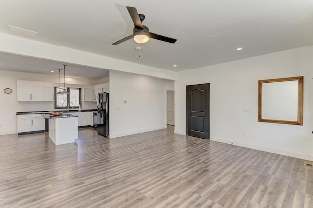 unfurnished living room featuring ceiling fan, sink, and light hardwood / wood-style flooring