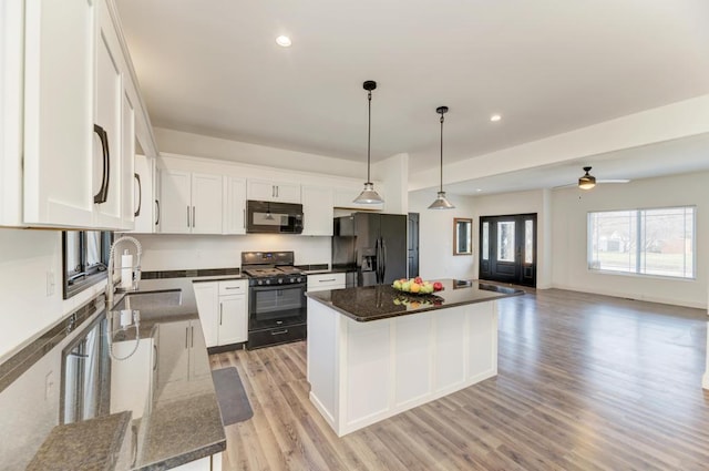 kitchen featuring black appliances, a center island, white cabinets, and light wood-type flooring