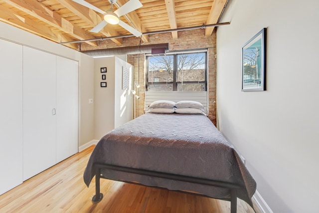 bedroom featuring light hardwood / wood-style flooring, wooden ceiling, a closet, ceiling fan, and beam ceiling