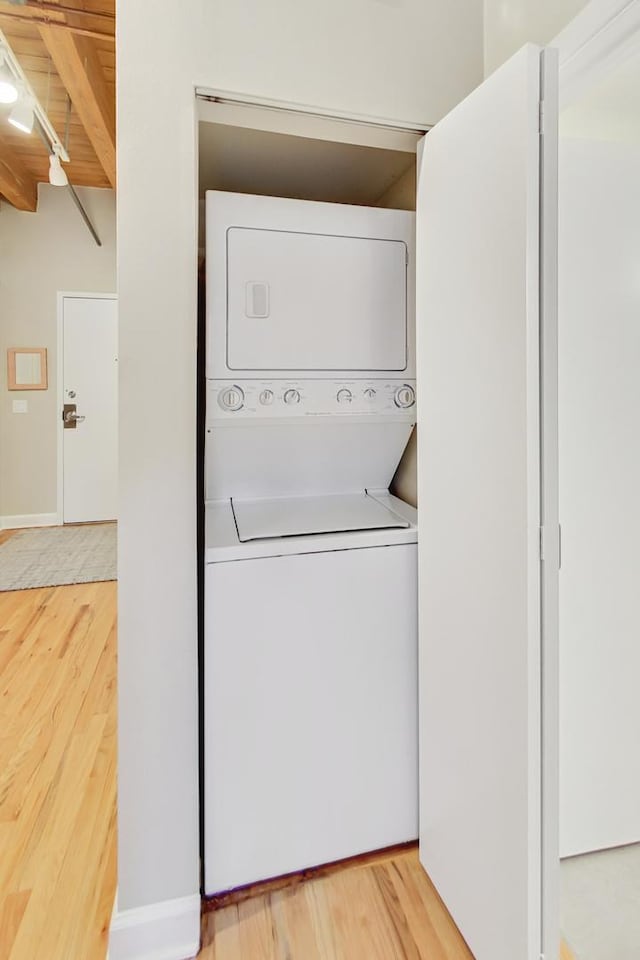 laundry area featuring hardwood / wood-style flooring and stacked washer and clothes dryer