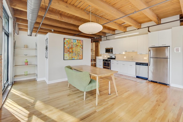 kitchen featuring light hardwood / wood-style flooring, hanging light fixtures, stainless steel appliances, decorative backsplash, and white cabinets