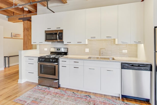 kitchen with white cabinetry, sink, decorative backsplash, and stainless steel appliances