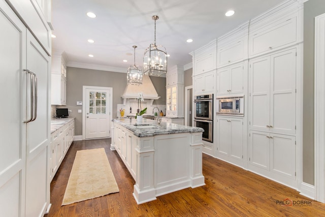 kitchen featuring white cabinetry, built in appliances, and an island with sink