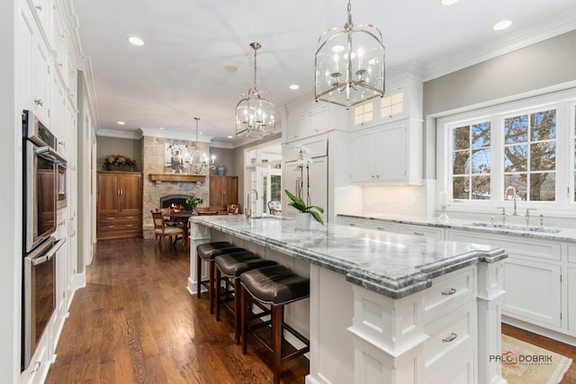 kitchen with white cabinetry, sink, a center island with sink, and pendant lighting