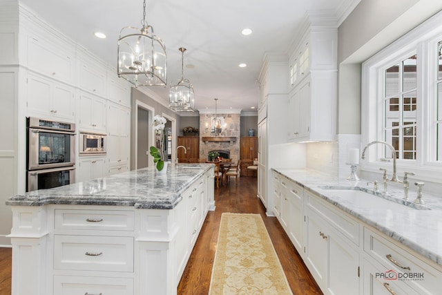 kitchen with hanging light fixtures, a large island, sink, and white cabinets