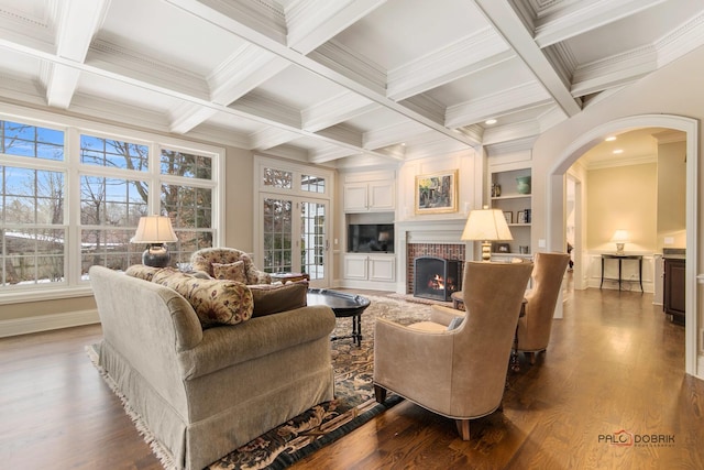 living room with dark hardwood / wood-style flooring, a brick fireplace, crown molding, and beam ceiling