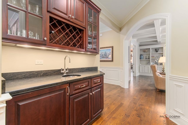 bar featuring built in shelves, dark wood-type flooring, sink, ornamental molding, and beamed ceiling