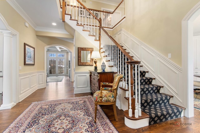 staircase with hardwood / wood-style flooring, ornamental molding, and decorative columns