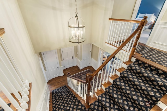 stairway featuring an inviting chandelier, hardwood / wood-style floors, and a high ceiling