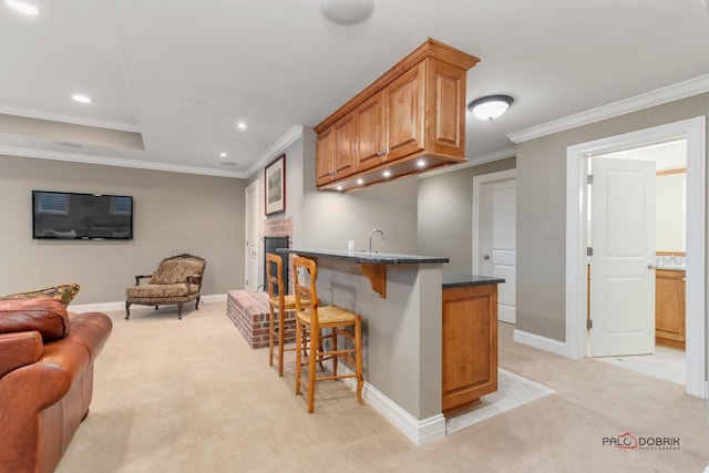 kitchen with sink, dark stone countertops, ornamental molding, a kitchen bar, and light carpet