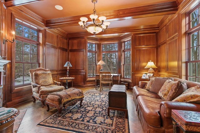 living area featuring crown molding, wood-type flooring, a chandelier, and wood walls