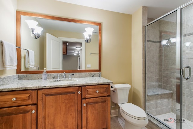 bathroom with vanity, a shower with shower door, and toilet