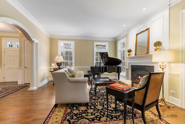 living room featuring ornamental molding, decorative columns, wood-type flooring, and plenty of natural light