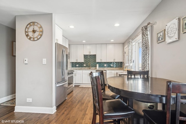 kitchen with decorative backsplash, sink, dark wood-type flooring, appliances with stainless steel finishes, and white cabinets