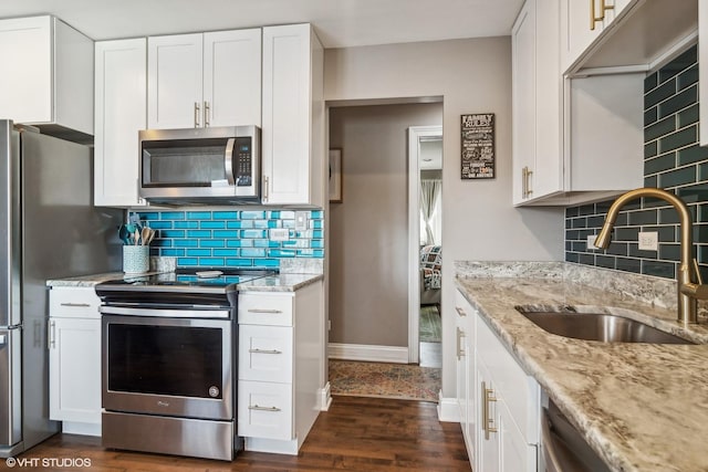 kitchen featuring light stone countertops, white cabinetry, dark hardwood / wood-style flooring, stainless steel appliances, and sink