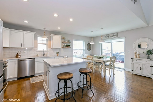 kitchen with hanging light fixtures, a kitchen island, stainless steel appliances, and a wealth of natural light