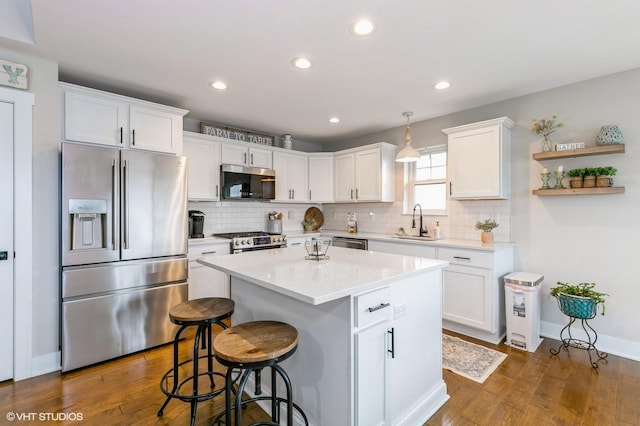 kitchen with dark hardwood / wood-style flooring, stainless steel appliances, sink, white cabinets, and a center island