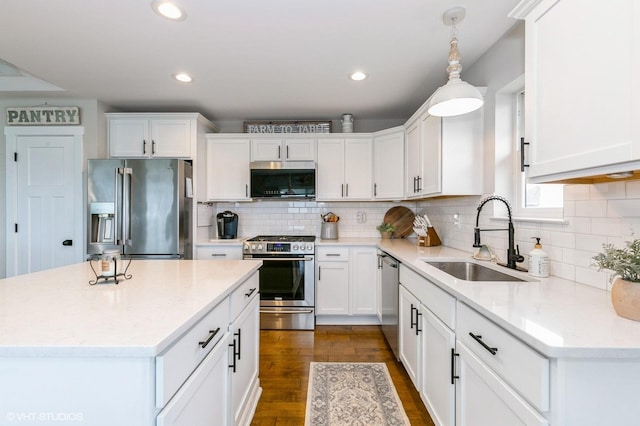 kitchen featuring stainless steel appliances, sink, decorative light fixtures, white cabinets, and dark hardwood / wood-style floors