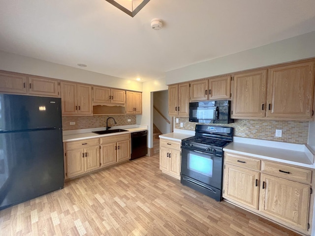 kitchen with decorative backsplash, sink, black appliances, and light hardwood / wood-style floors