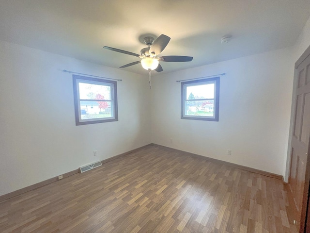 unfurnished room featuring wood-type flooring, plenty of natural light, and ceiling fan