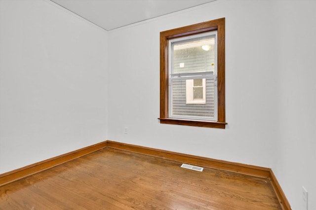 spare room featuring wood-type flooring and crown molding