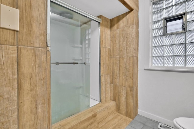 bathroom featuring tile patterned floors, toilet, and a shower with shower door