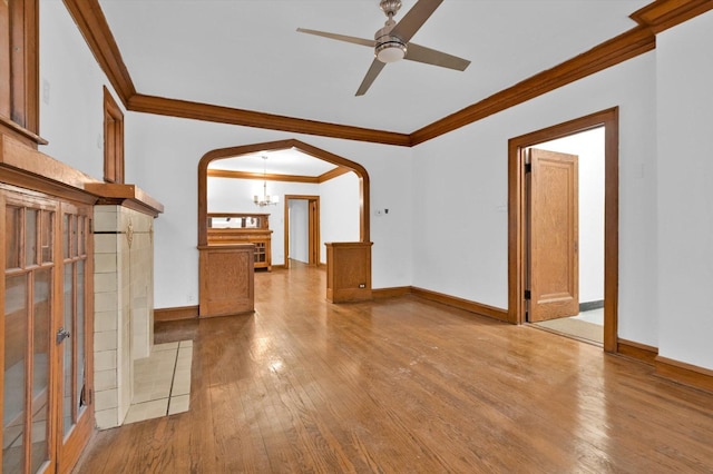 unfurnished living room with hardwood / wood-style floors, ceiling fan with notable chandelier, and ornamental molding