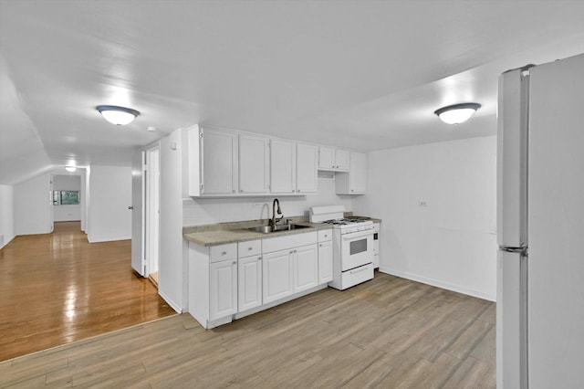 kitchen with white cabinetry, sink, light hardwood / wood-style floors, and white appliances