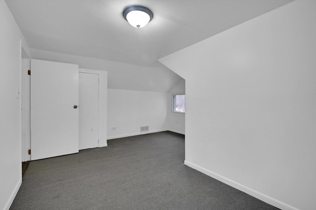 additional living space featuring vaulted ceiling and dark carpet