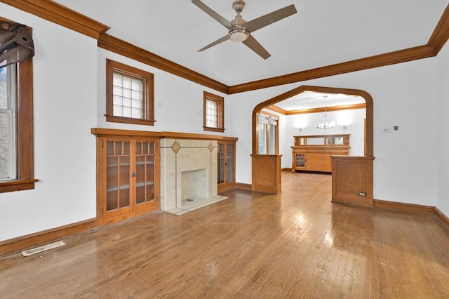 unfurnished living room with ceiling fan with notable chandelier, wood-type flooring, and crown molding