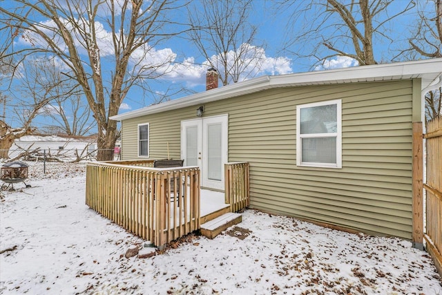 snow covered property with french doors and a wooden deck