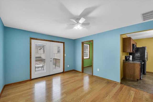 empty room with light hardwood / wood-style floors, a wealth of natural light, and french doors