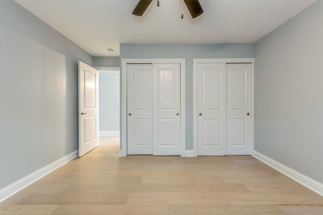 unfurnished bedroom featuring two closets, light hardwood / wood-style flooring, and ceiling fan