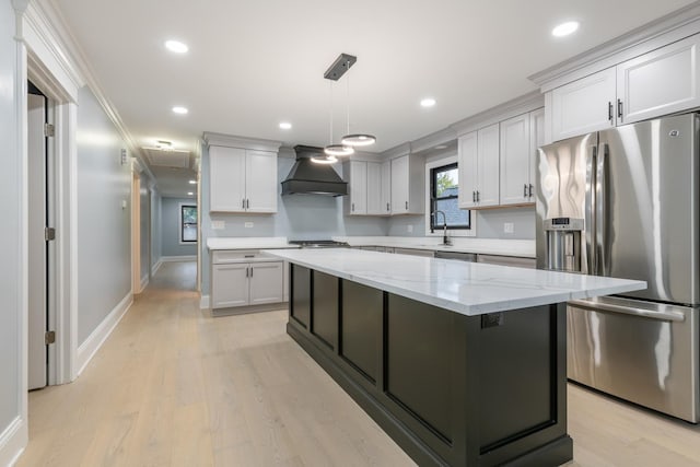 kitchen with stainless steel fridge, custom exhaust hood, decorative light fixtures, a center island, and light hardwood / wood-style floors