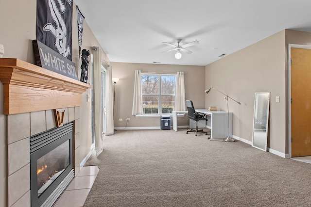 unfurnished office featuring a fireplace, light colored carpet, and ceiling fan