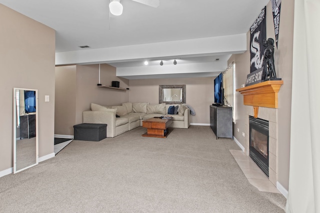 living room with a tiled fireplace, ceiling fan, and light colored carpet