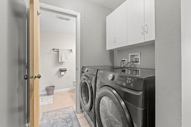 laundry area with cabinets, light tile patterned floors, and washing machine and clothes dryer