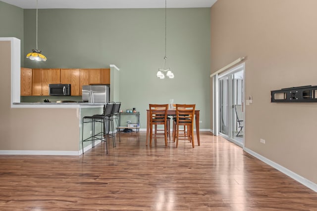 dining room featuring hardwood / wood-style floors, a towering ceiling, and a chandelier