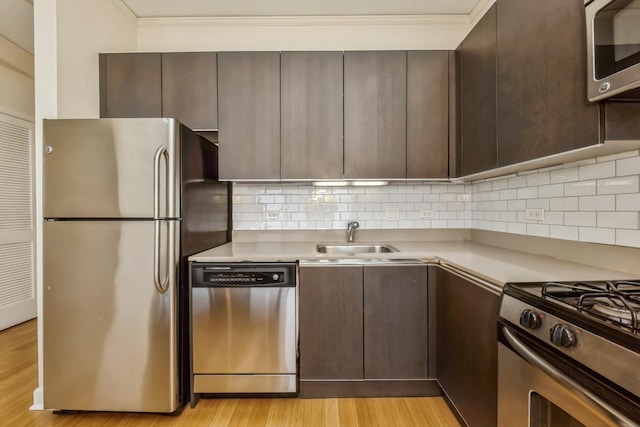 kitchen with backsplash, light hardwood / wood-style flooring, stainless steel appliances, and sink