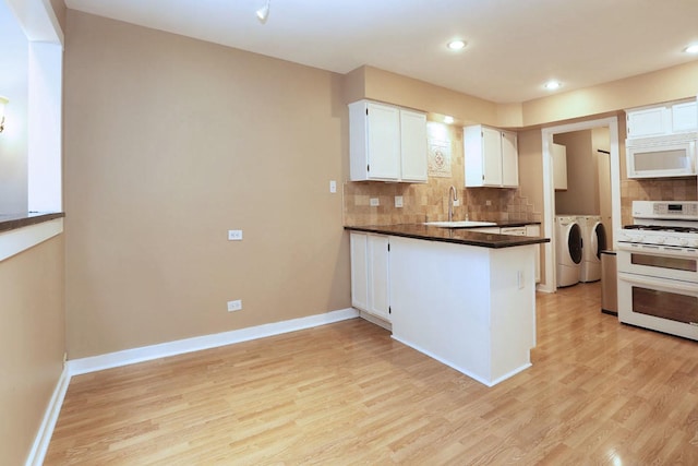 kitchen with white appliances, white cabinets, sink, washer and dryer, and light wood-type flooring