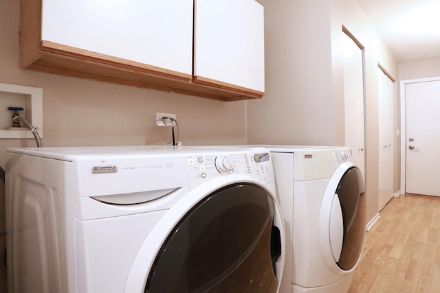 washroom featuring washing machine and clothes dryer, cabinets, and light wood-type flooring