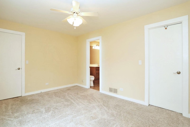 unfurnished bedroom with connected bathroom, light carpet, and ceiling fan